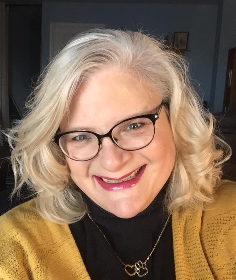 a woman wearing black and gold, smiling with red lipstick on and black glasses
