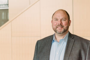 portrait of Steve Caruso in blazer and collared shirt in front of beige wall