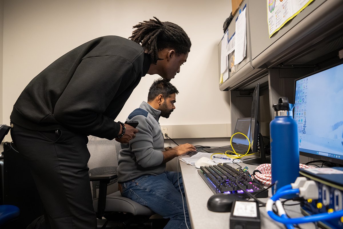 Chris Dollo (left), a senior computer science major and undergraduate researcher in the Vinjamuri lab, and Parthan Olikkal (right) work at the computer. Olikkal brought the concept of capturing hand movements using cameras into the lab, a key step toward making cost-effective technologies.