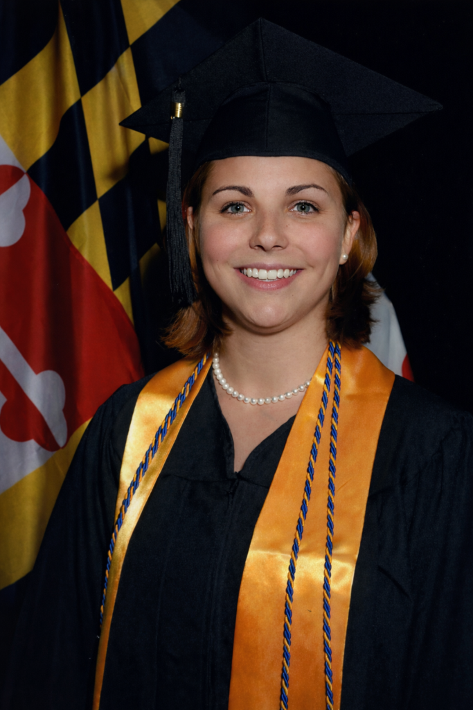woman in commencement regalia, Maryland flag in background