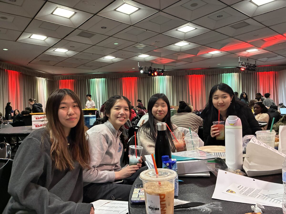 four girls sitting at a table surrounded by papers and snacks