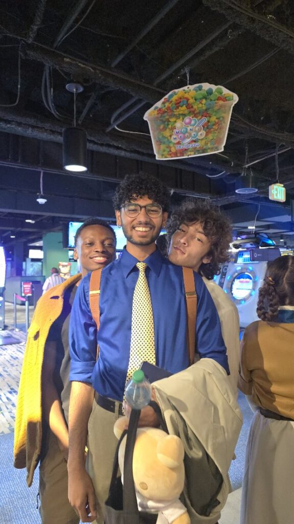 three students in professional clothes at an arcade carrying bags