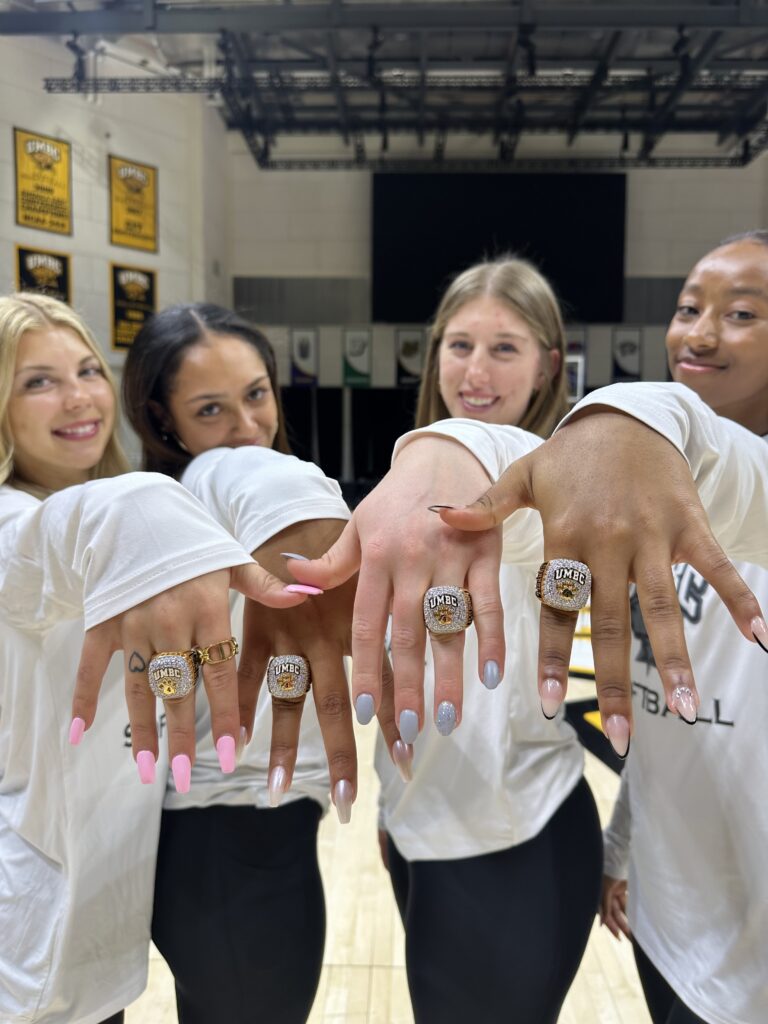 Four women show off their team rings to the camera