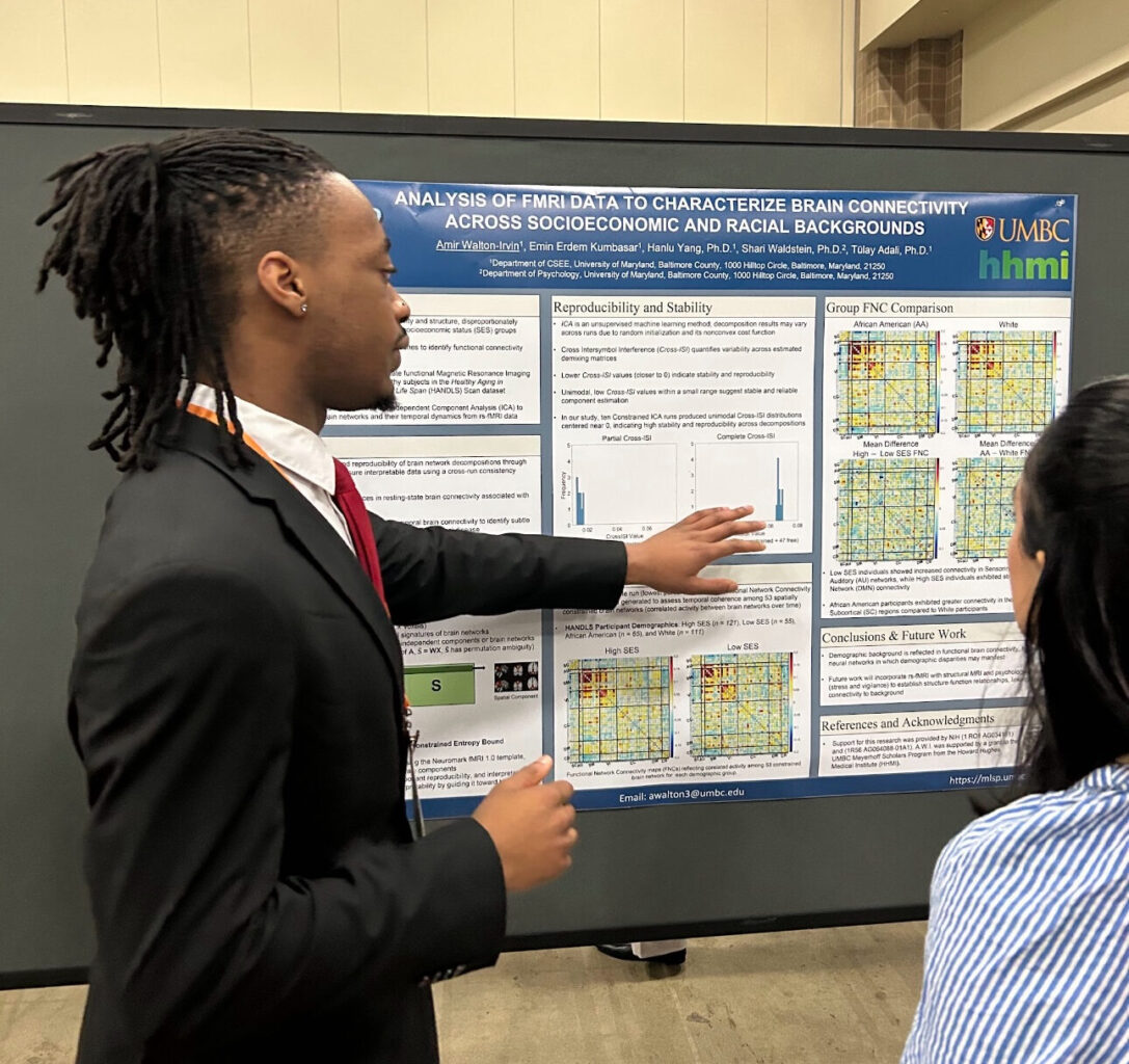 Student in a suit presents at scientific poster.