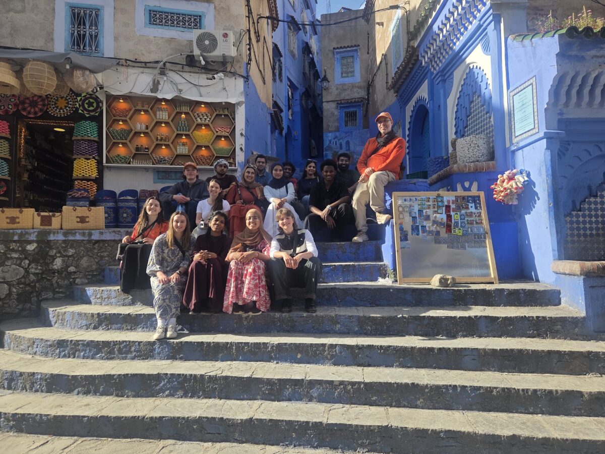 A group of students sit on cement stairs outside as they travel through Morocco 