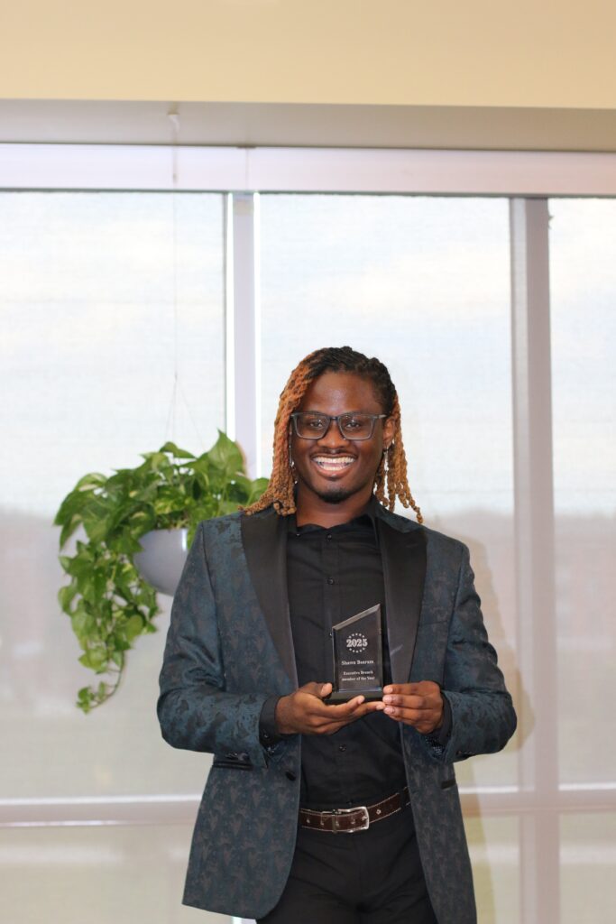 Sean Bearam smiling, holding an award.