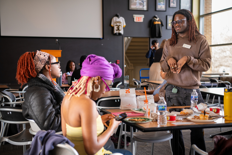 Three people talking at a table with food.