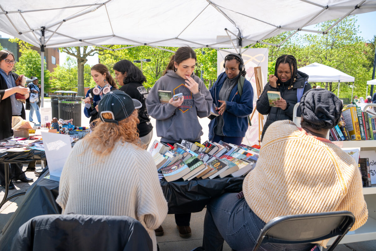 students check out a table full of books under an EZ-up at BookFest