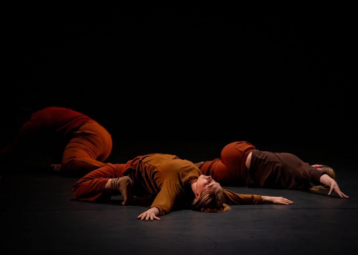 Three dancers perform on stage.