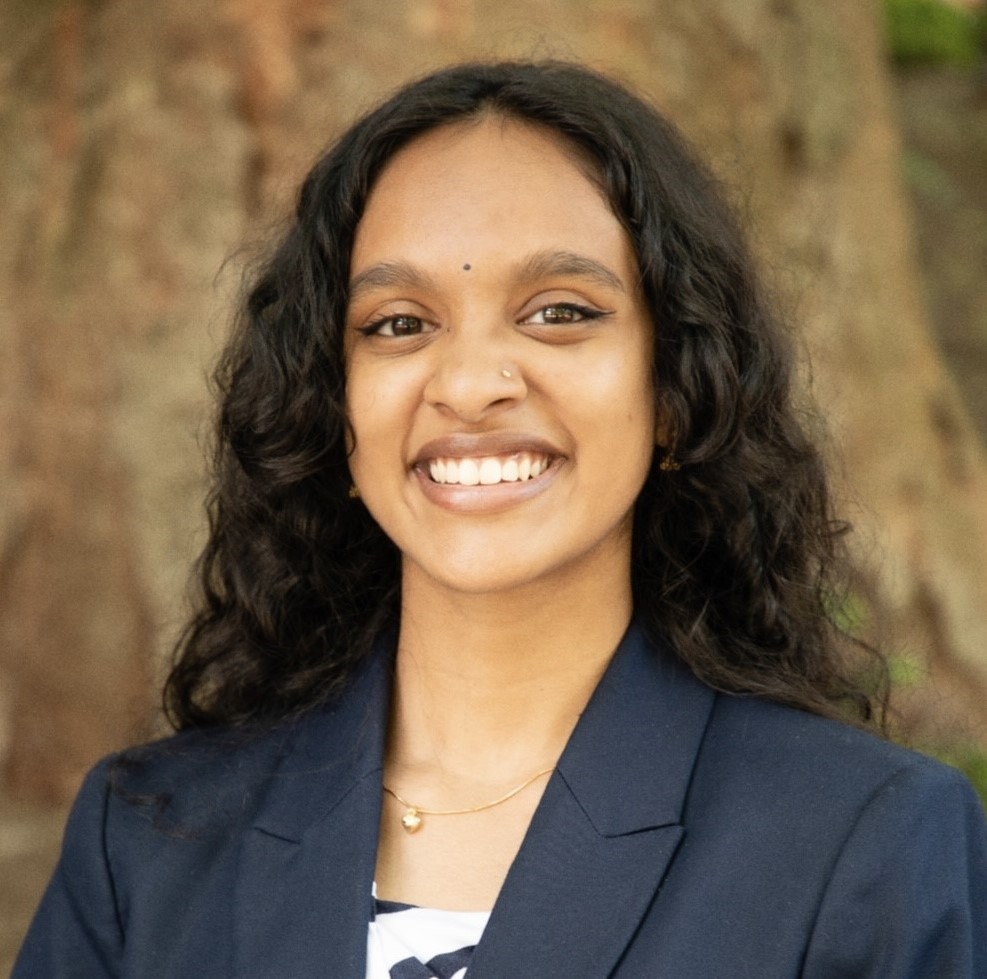 A student smiles for a headshot in front of a tree