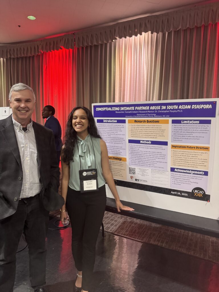 A student stands with a professor in front of a poster presentation 