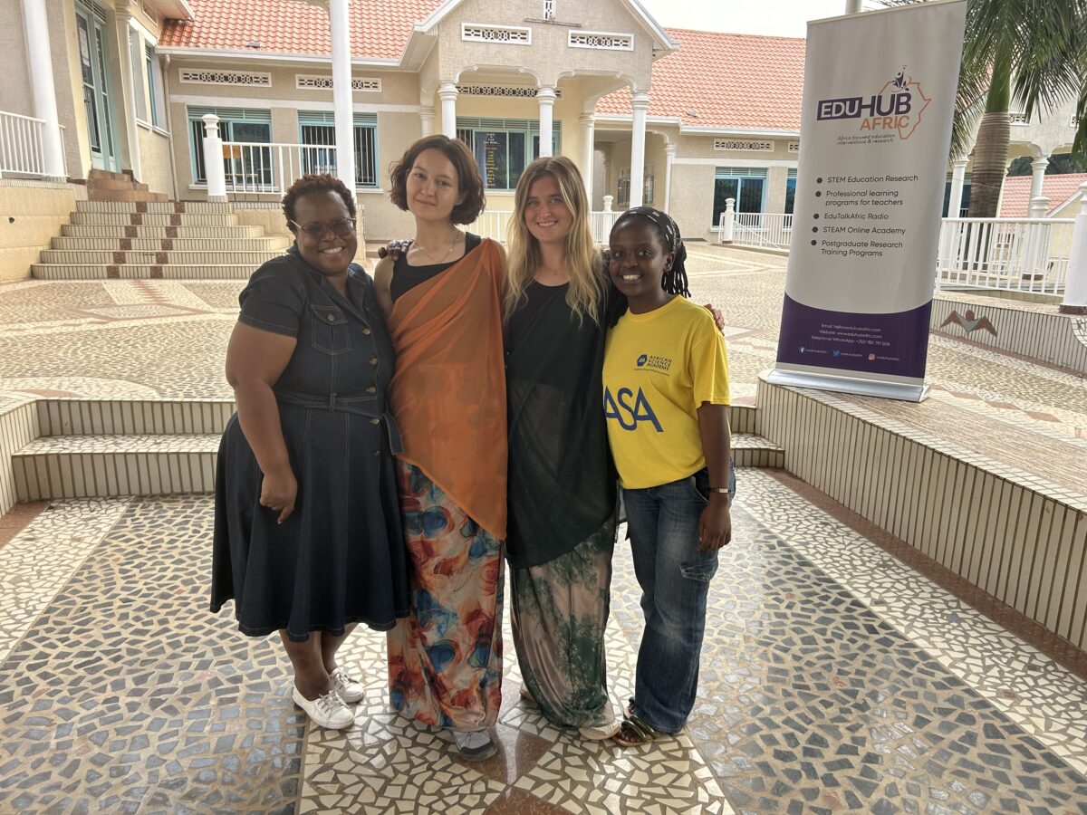 four women including Rileigh Mansfield; two in traditional African dress and one in a t-shirt that reads "African Science Academy"