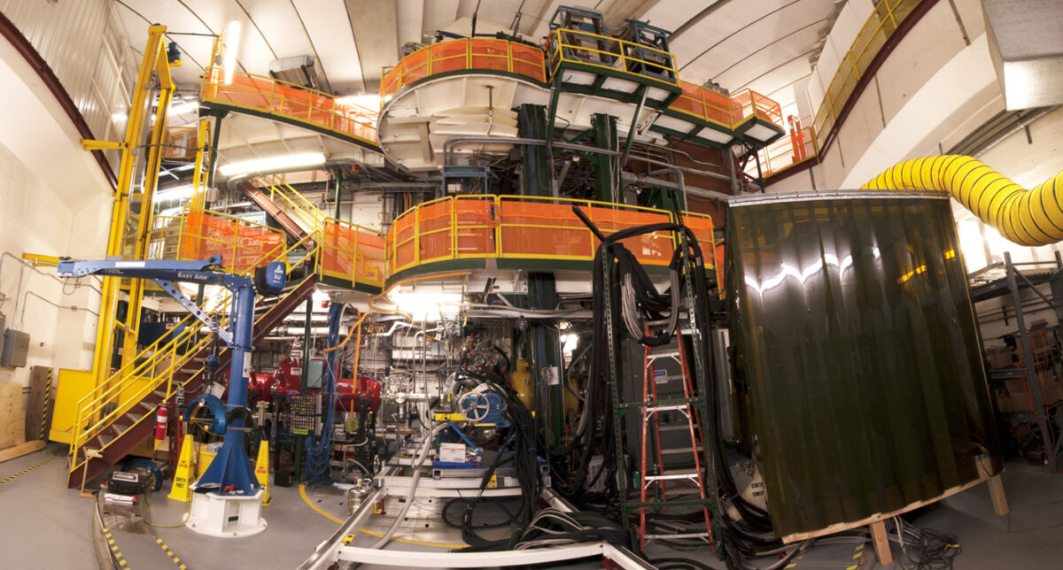 huge, complicated instrument in orange and black, ladder in front and lots of equipment behind; the instrument on which the team will mimic cosmic ray reactions