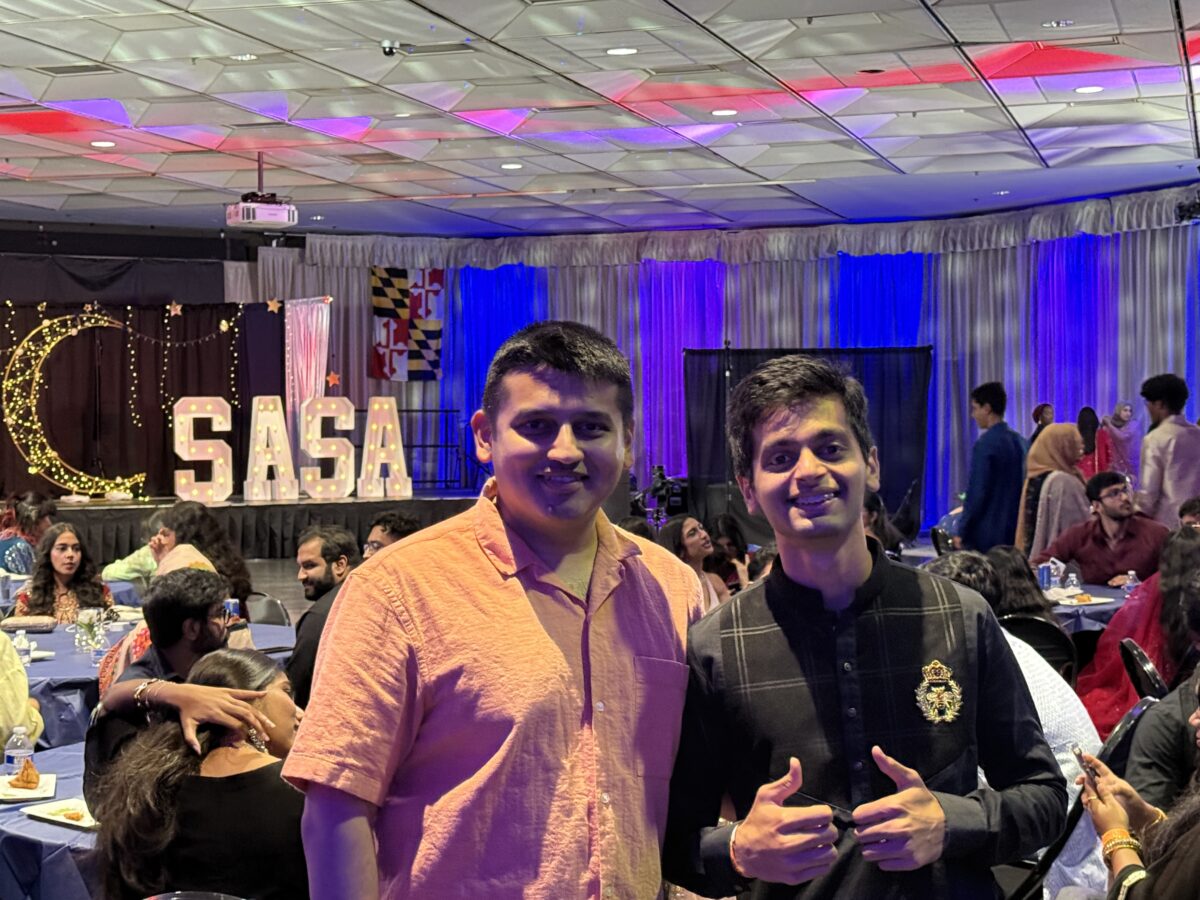 Two students stand in front of large block SASA letters at a community celebration