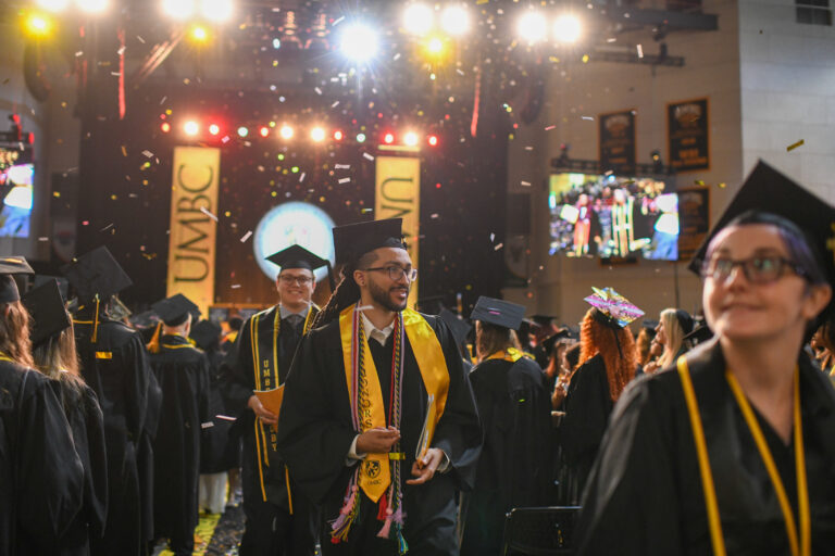 students exit the commencement ceremony while confetti falls from the ceiling