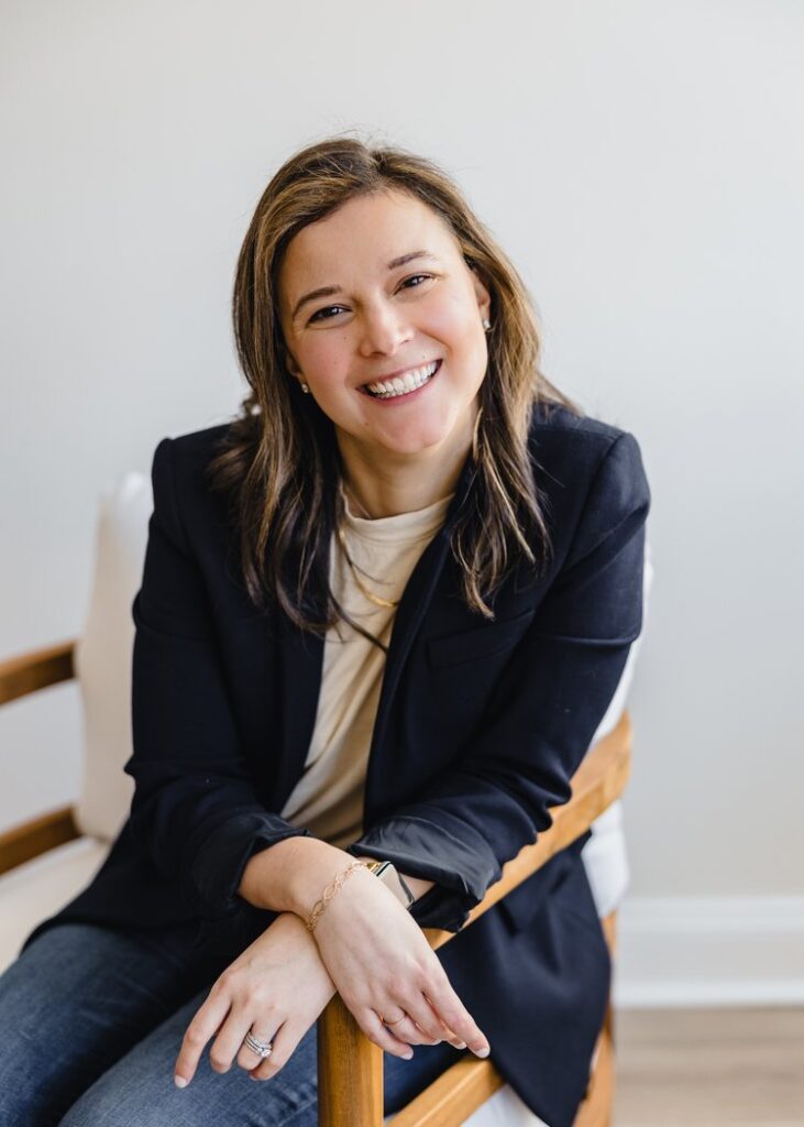 Headshot of a person smiling while seated in a chair.