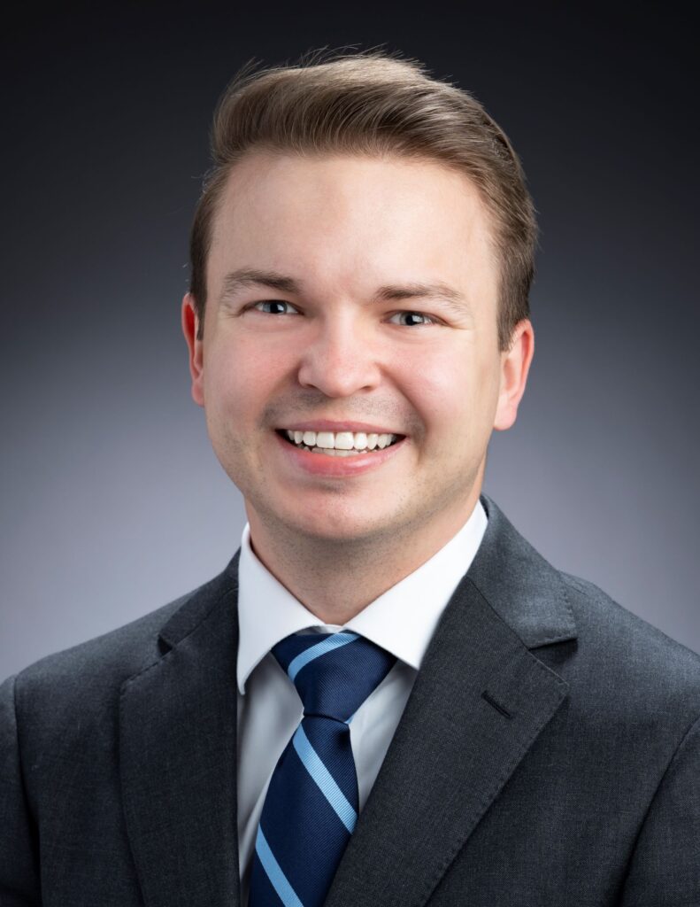 Headshot of a person wearing a suit and tie.