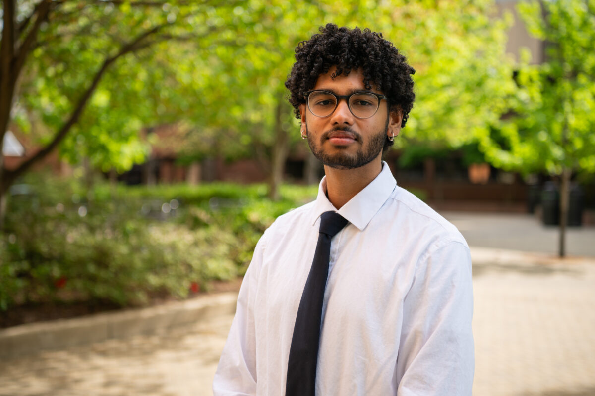 a headshot of a manav narendra, a college senior wearing a white collared shirt with a black tie