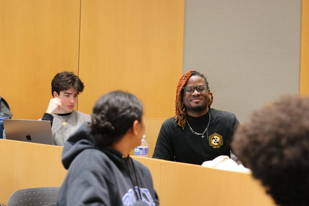 a classroom in discussion with the focus on a college student in a black turtle neck