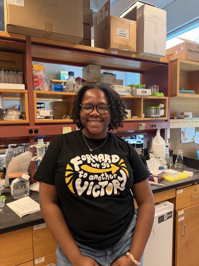 Nina-Simone Hunter smiles at the camera standing near a lab bench