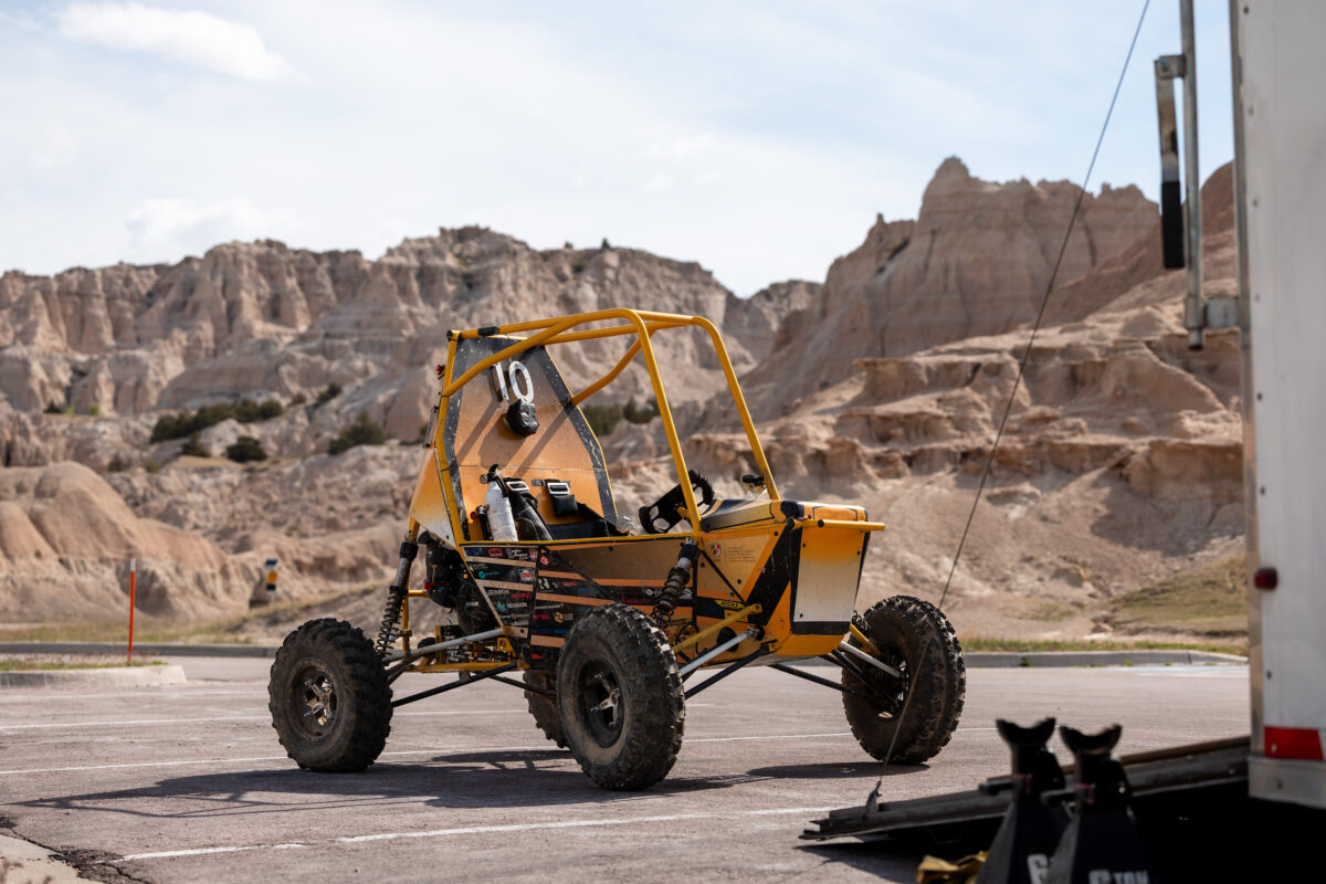 Off-road Baja car in parking lot in front of scenic rock landscape