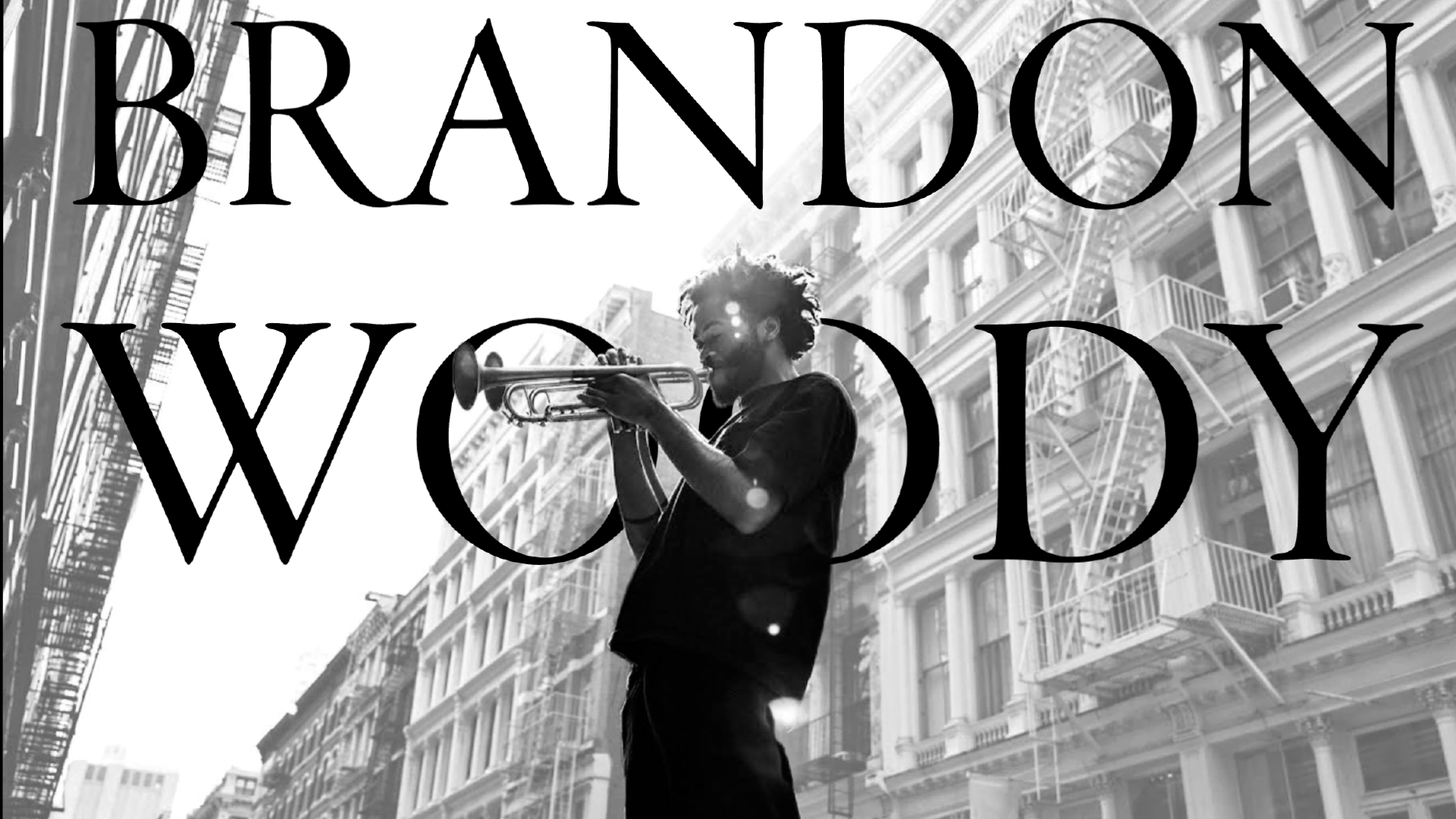 A person plays a trumpet in a city street. The text reads "BRANDON WOODY."