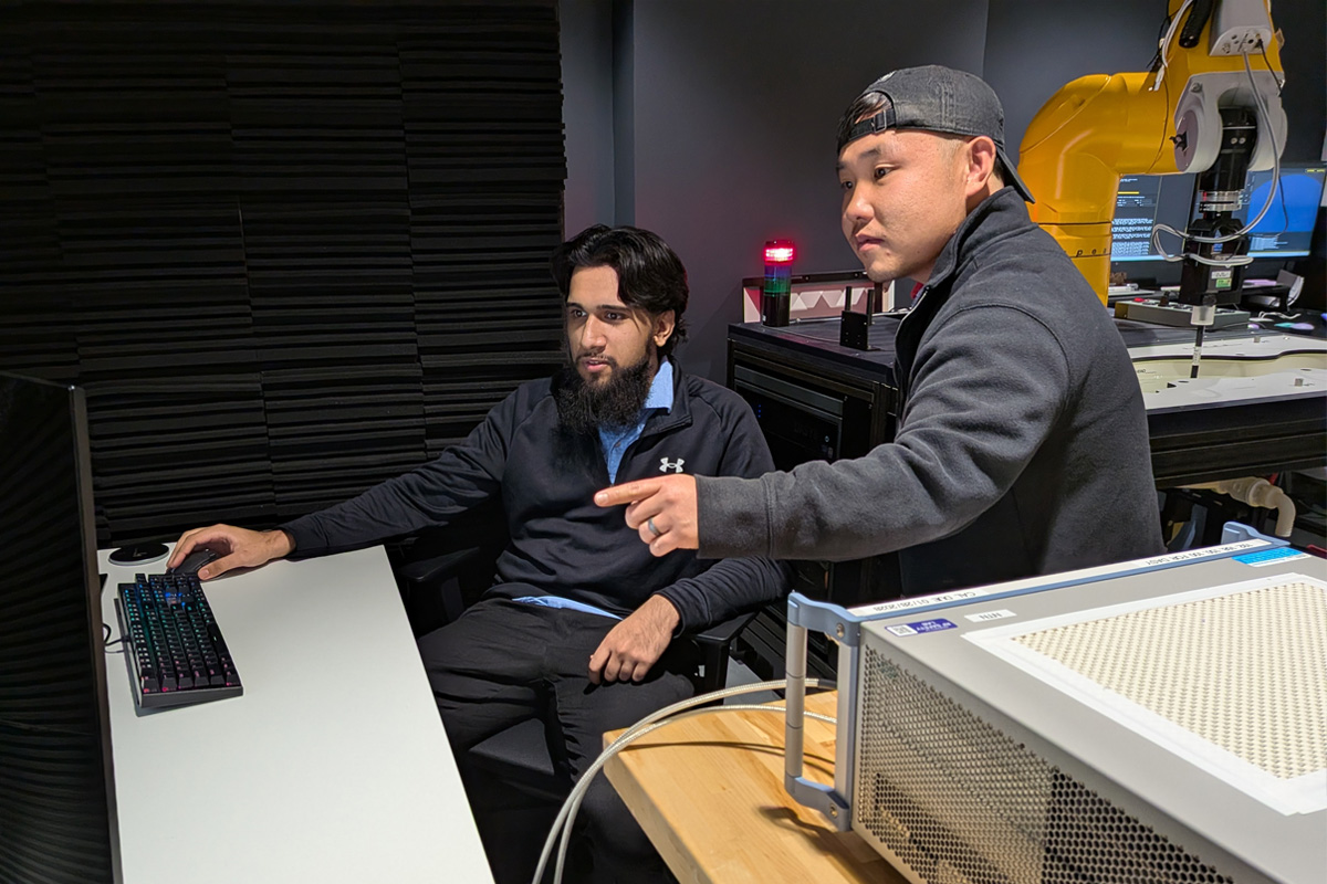Student and internship mentor in the lab looking at computer screen.