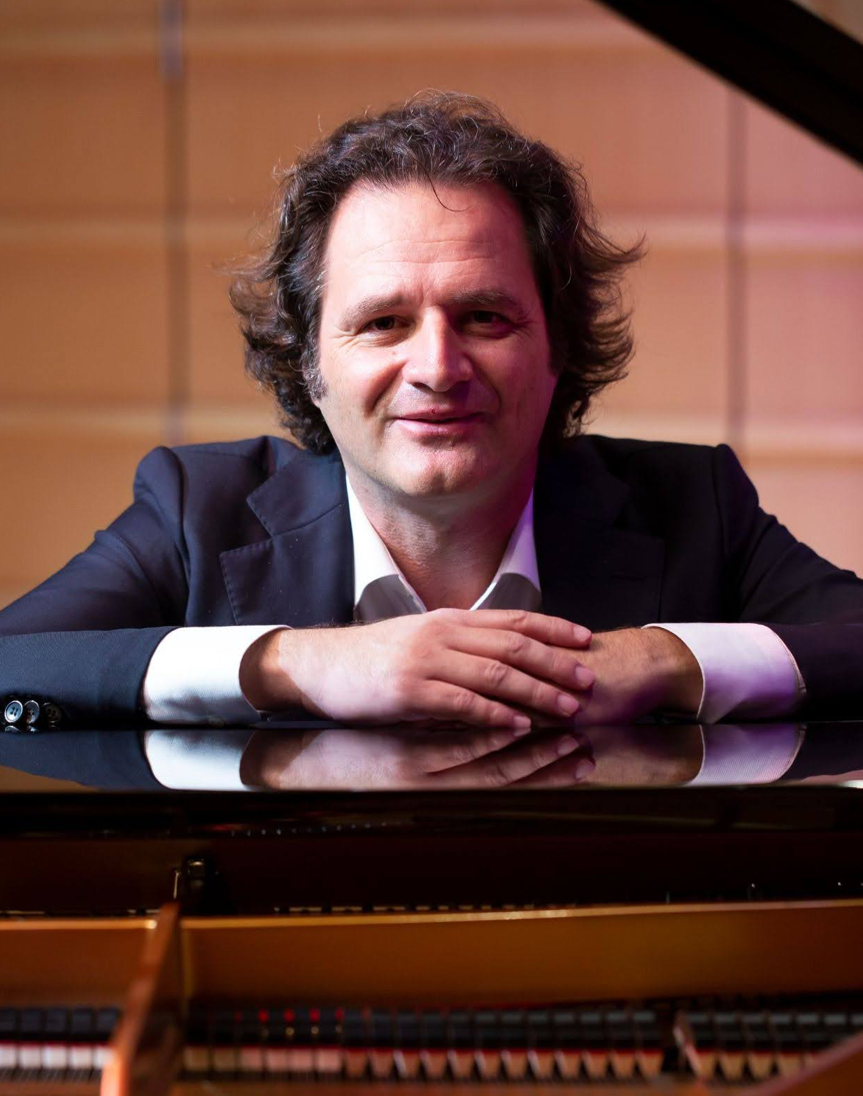 Headshot of a person leaning on a piano.