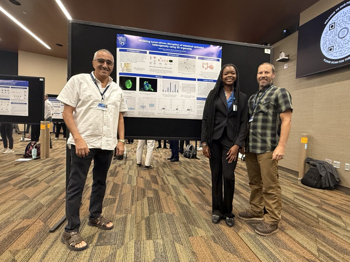 Zainab Idowu stands beside her research poster with two mentors from her Mayo Clinic internship