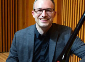 Headshot of a person wearing glasses and a blazer smiling.