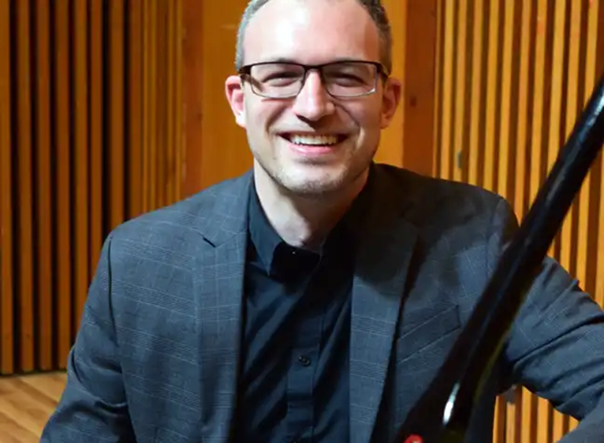 Headshot of a person wearing glasses and a blazer smiling.