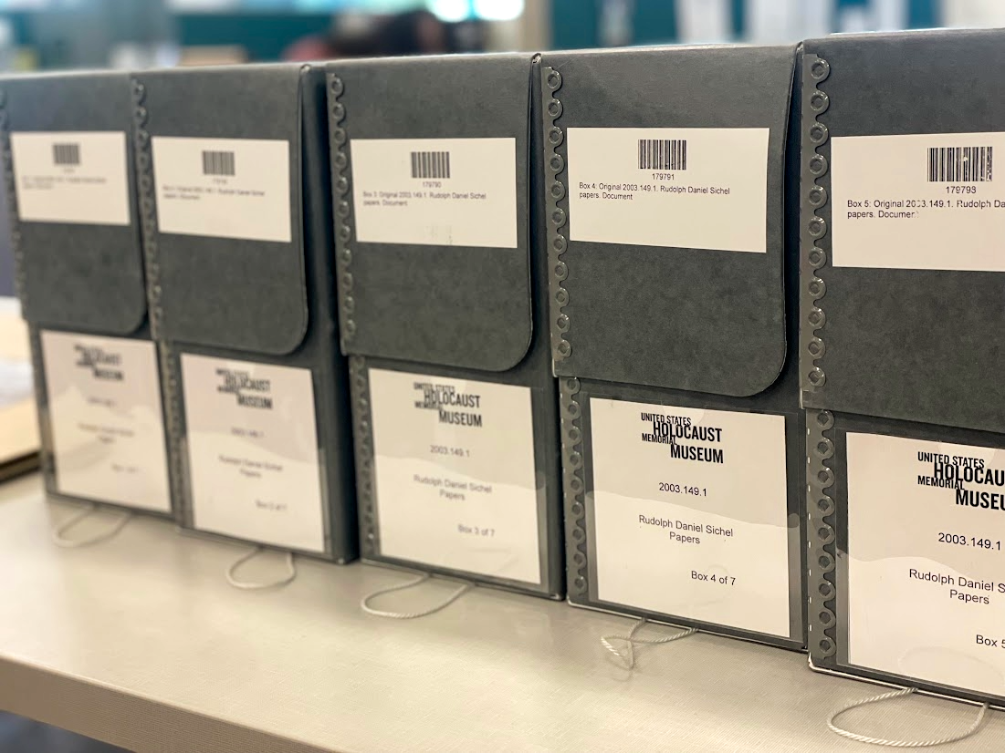 Five grey rectangular archival file boxes with bar code lables and a United States Holocaust Memorial Museum