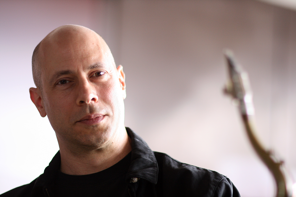 Headshot of a person with a saxophone in the foreground.