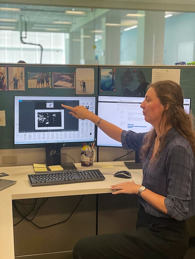 Reese Finnigan pointing to a computer screen displaying a black and white photo at the United States Holocaust Memorial Museum Shapell Family Collections, Conservation and Research Center in Bowie, Maryland