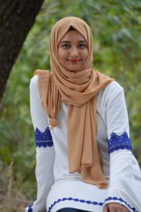 Headshot of Amina Mahmood wearing a head covering.