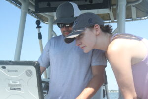 Liliana Bowman and Rob Aguilar on a boat looking at a computer screen