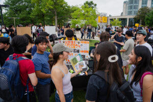 Thousands of students walk around tables set up on a side walk looking at information about student clubs at iFest