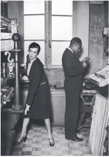 A black and white picture of a woman and a man dressed in business suits working in a room with a printing press