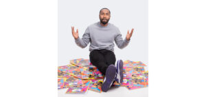 A person sitting on the floor with hands raised, surrounded by numerous colorful illustrated storybooks.