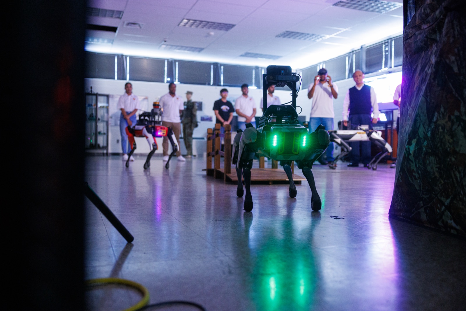 Students and visitors watch a four-legged robot walk across a UMBC lab floor
